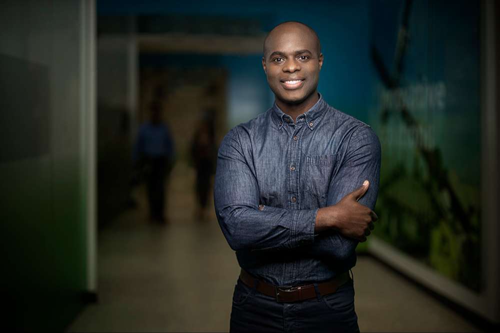 An SCE employee standing in a dark hallway smiling at the camera