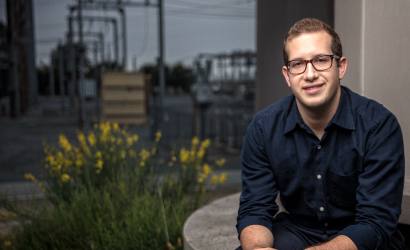 A smiling young man with glasses looking at the camera