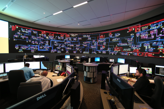 A room with large monitors and employees looking at them and working