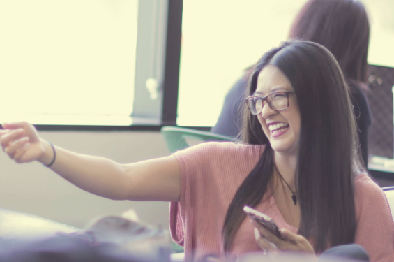 A woman smiling and holding a phone on one hand