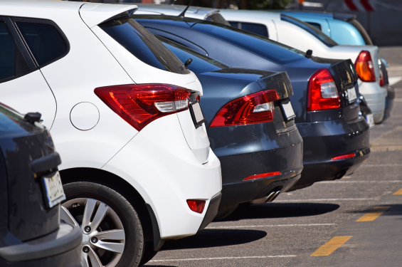 Side and rear view of six cars parked in parking lot spots