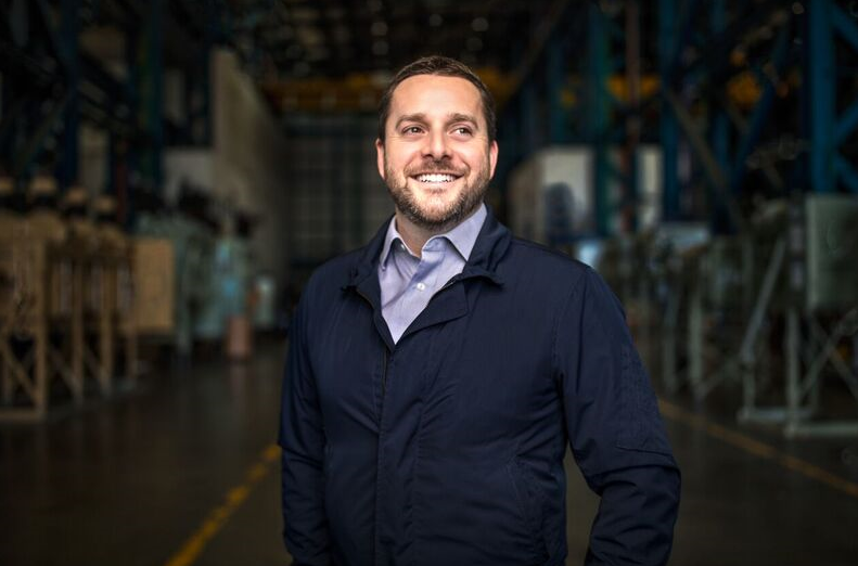 Man smiling and standing in a warehouse type setting