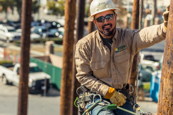 Shot of a lineman worker at work smiling and securely suspended with ropes