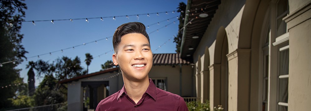 A man in front of a building smiling away from the camera