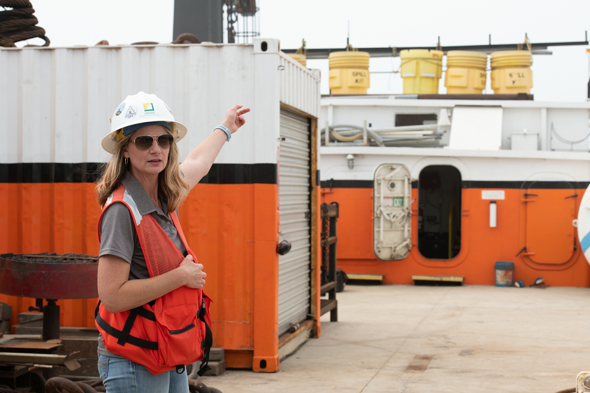 A woman wearing a hard hat pointing behind her