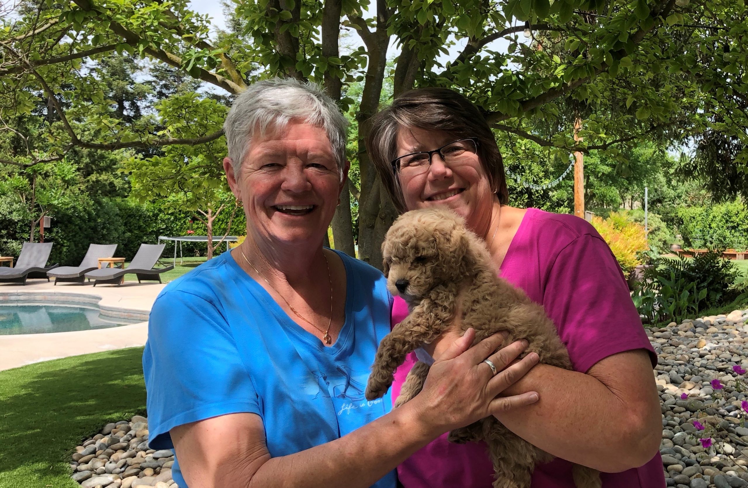 Two women smiling holding a dog