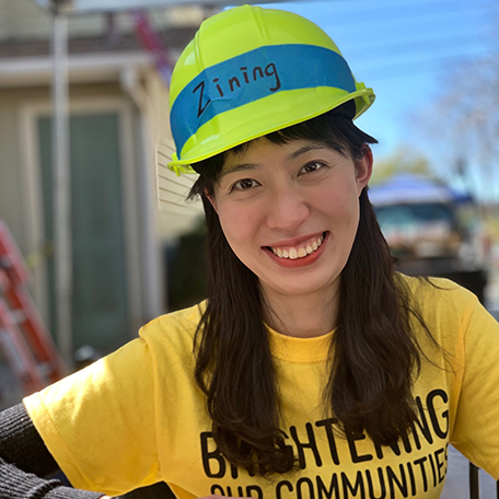 A young lady with a yellow, construction hard hat smiling