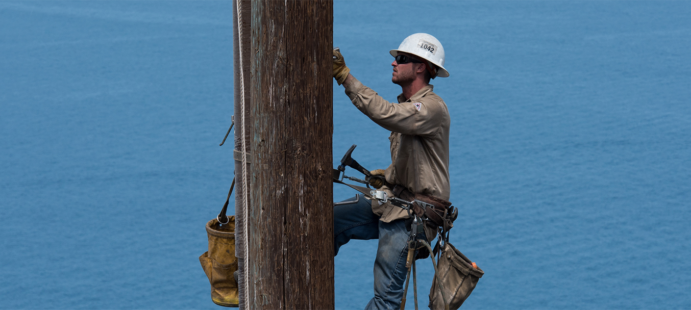 Aerial image of a lineman working on an electrical pole.