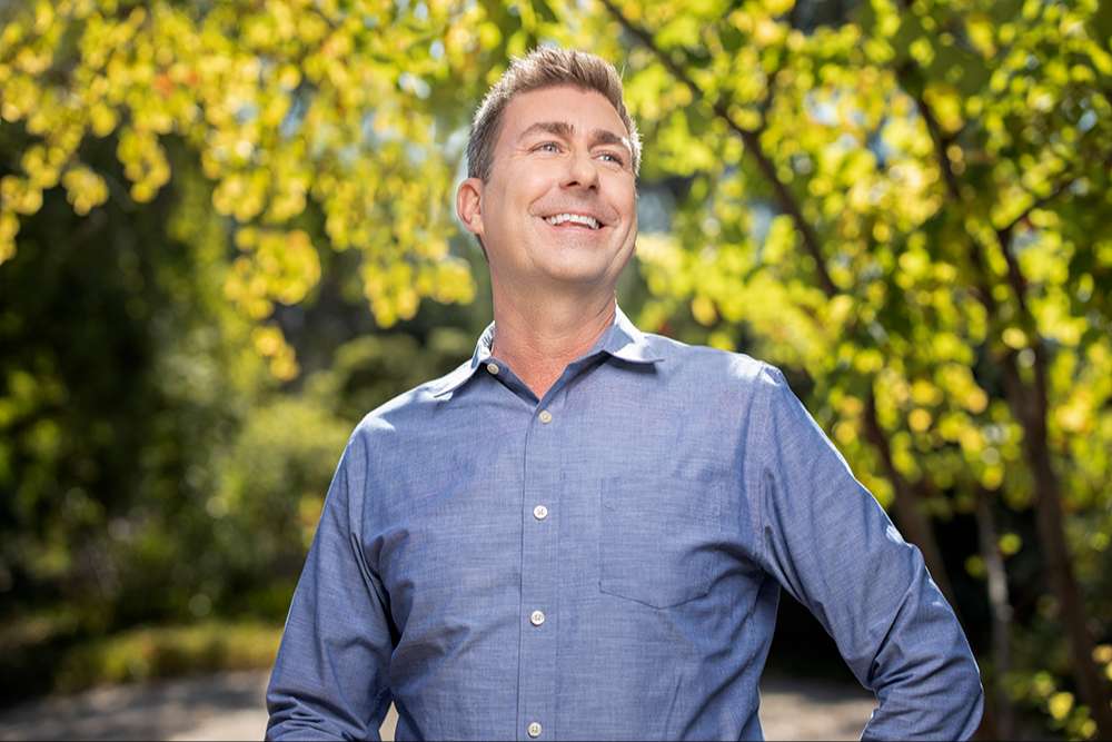 An SCE employee outdoors in a sunny tree lined area