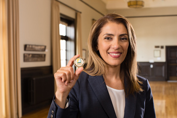A happy woman holding up a military service coin