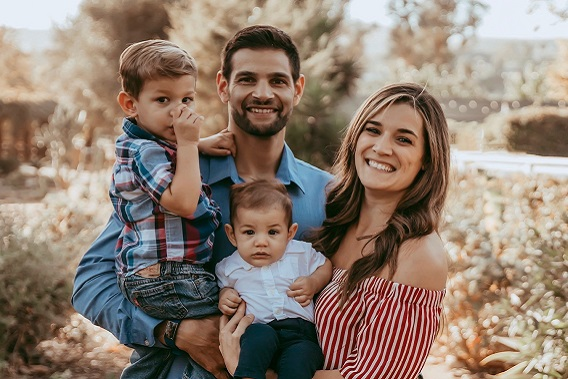 Family photo of husband and wife holding toddler and newborn boys