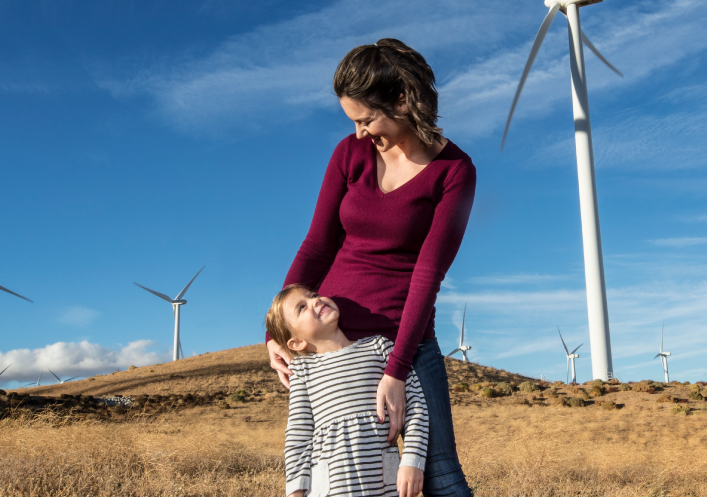 A woman and a young girl in a field with windmills