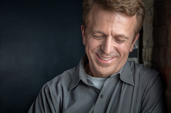 A man leaning towards a wall smiling