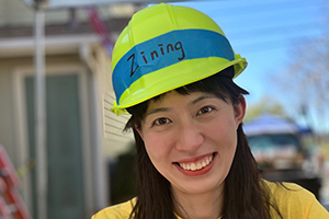 A woman smiling with a hard hat on